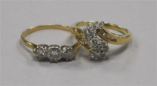 An 18ct gold and three stone diamond ring and an 18ct gold and diamond cluster ring.